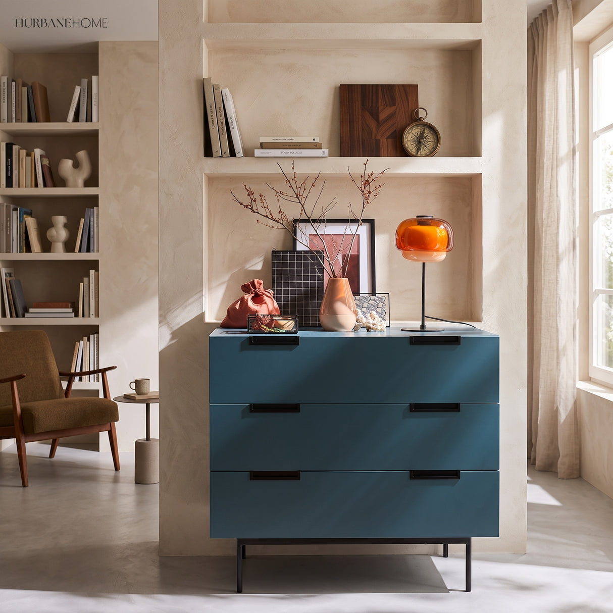 Unlit amber glass table lamp on a teal dresser in a bright plaster room