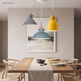 Grey, blue and yellow wood pendant lights clustered over a light oak dining table