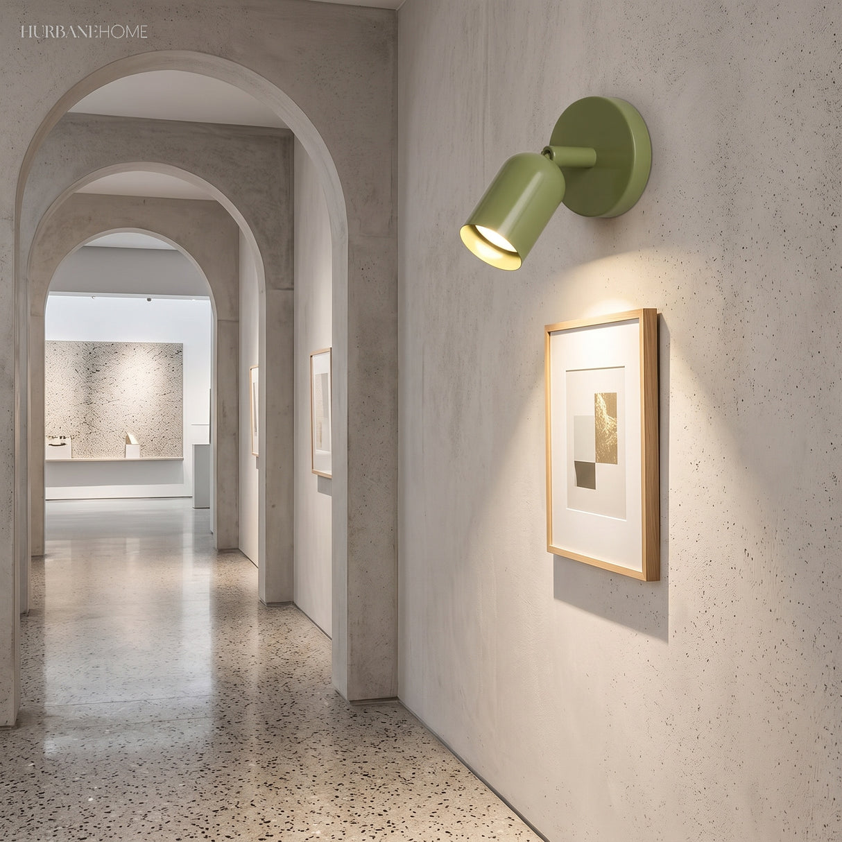 Green rotatable spotlight sconce lighting a framed print in a plaster hallway