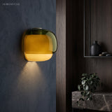 Green dual-tone glass wall sconce lit against a dark blue plaster wall