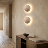 Two stone wall sconces glowing on a plaster hallway wall above a console