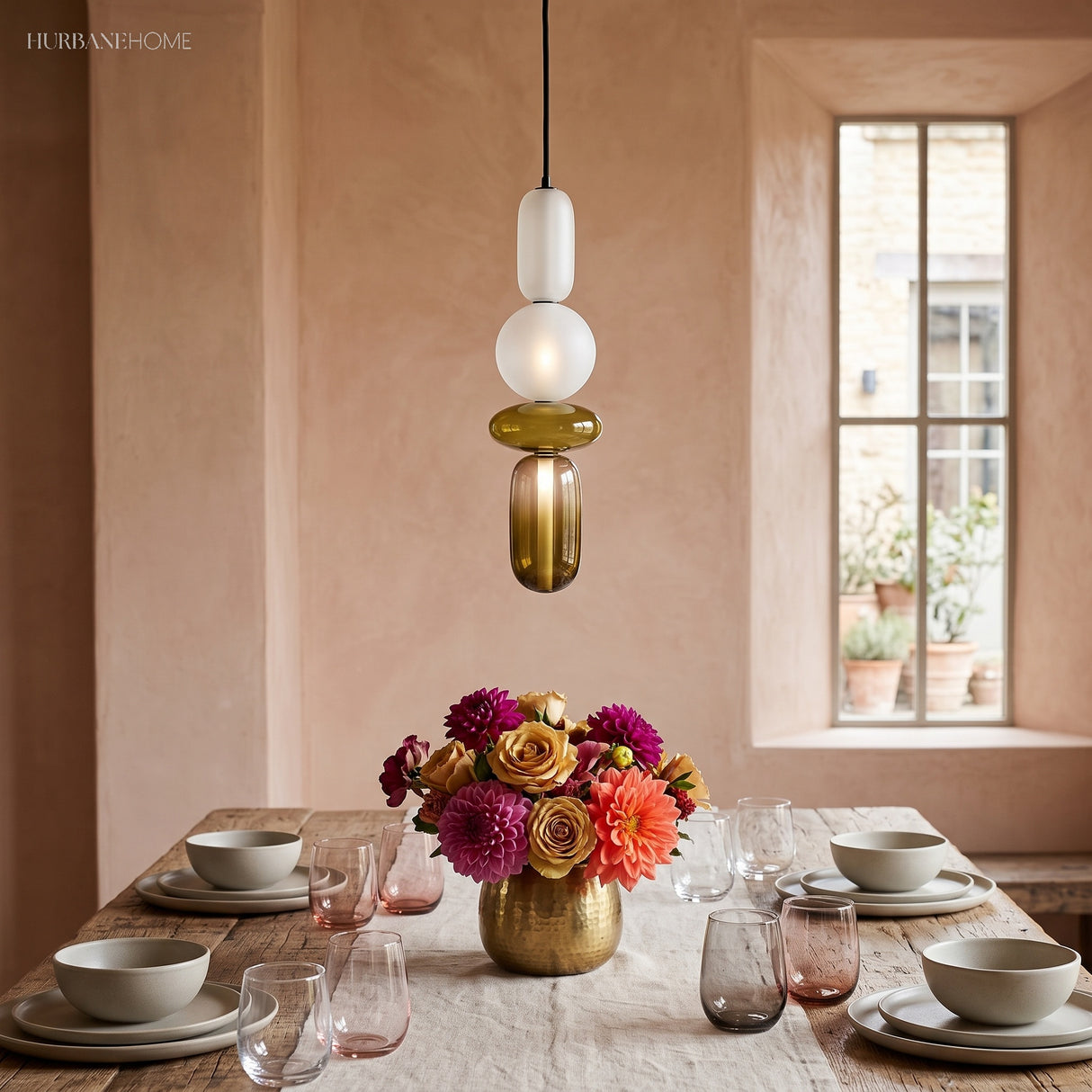 Cluster of three colorful glass pendant lights above a travertine table with tulips