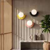 Yellow, black and pink wall sconces grouped on a concrete wall