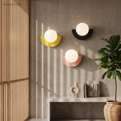 Yellow, black and pink wall sconces grouped on a concrete wall