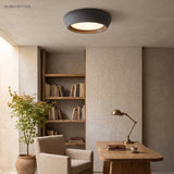 Brown toned flush mount ceiling light above a wooden study with brass task lamp
