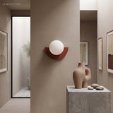 Deep red glass globe wall light on a warm plaster hallway wall