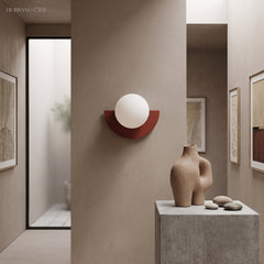 Deep red glass globe wall light on a warm plaster hallway wall
