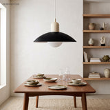 Modern disc pendant light hanging in a bright minimalist living corner