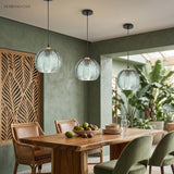 Trio of green glass globe pendants clustered above a dining table in a sage green room