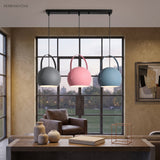 Grey, pink, and blue ball pendant lights in a row by a window