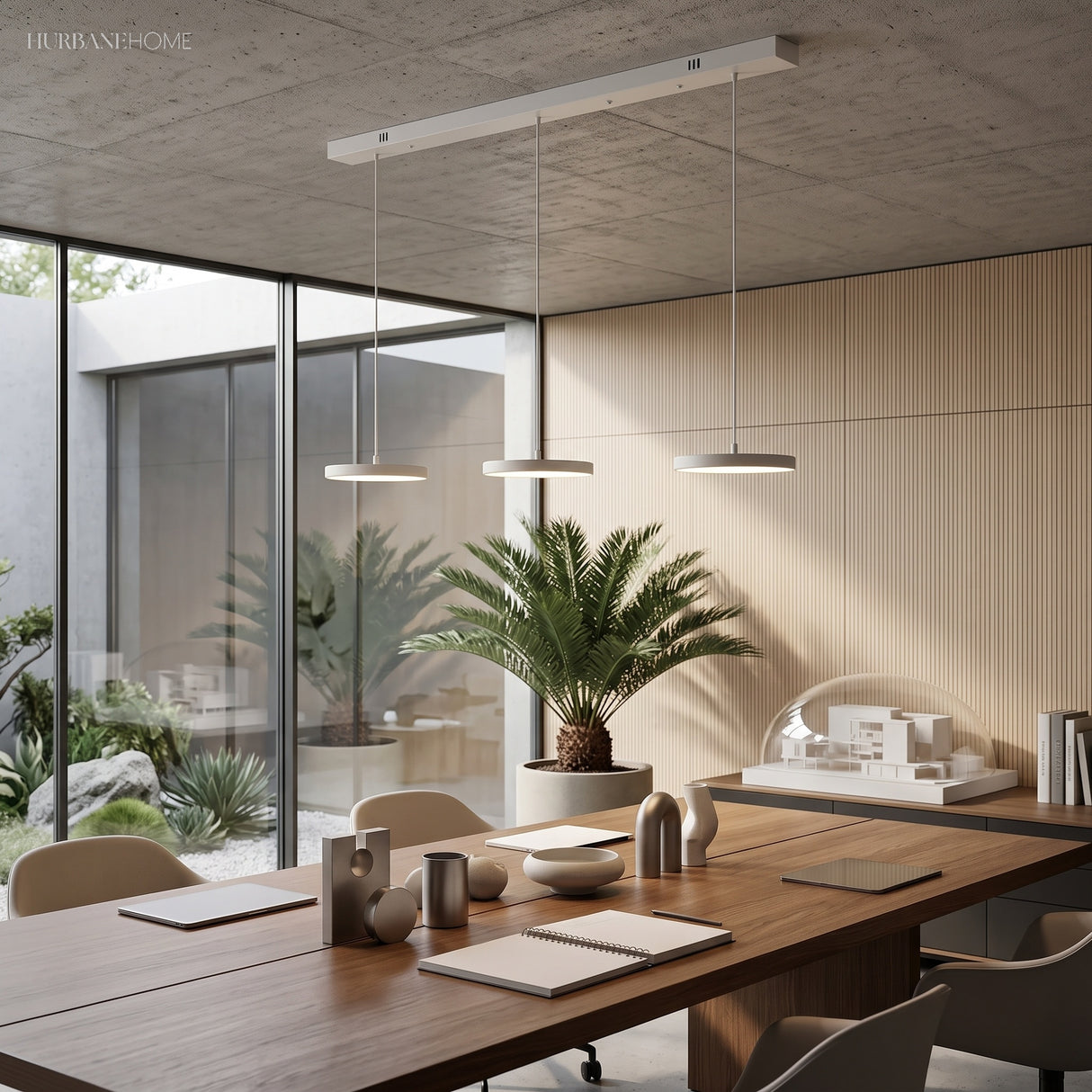Three slim pendant discs above a walnut dining table beside a courtyard window