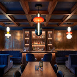 White and amber glass pendant light over a rustic dining table set for a meal