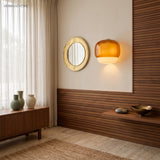 Amber wall sconce beside a round mirror on warm walnut slat panelling