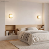 Two yellow orb wall sconces framing a bed headboard as bedside reading lights