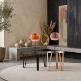 Amber and pink glass table lamps side by side on two low coffee tables