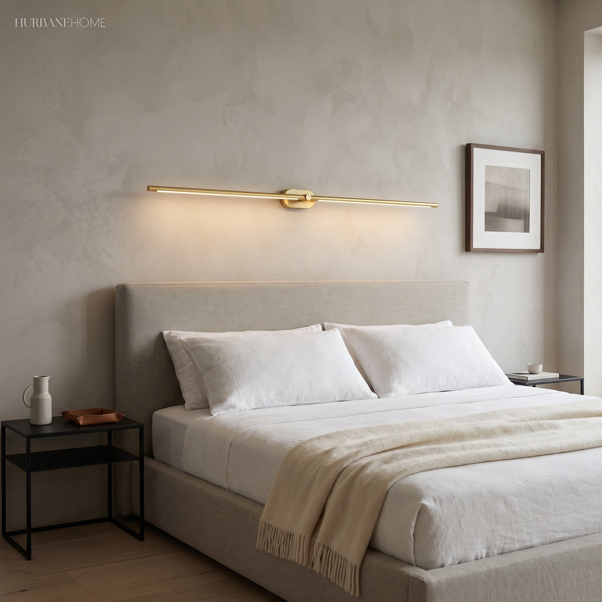 Gold linear LED sconce mounted horizontally above an upholstered bed