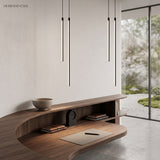Four slim black tube pendants glowing warm white above a walnut desk