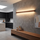 Wood linear light lit above a floating oak desk beside a bookcase and chair