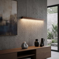 Walnut linear wall light lit above a timber vanity and framed bathroom mirror