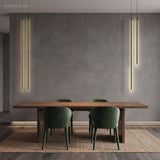 Black linear pendant lights flanking a grey wall over a wood dining table