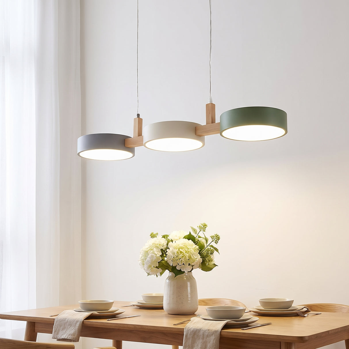Linear pendant light with grey, cream and green drum shades above an oak dining table