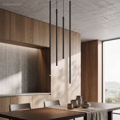 Staggered black tube pendant lights above a dining table in a wood kitchen