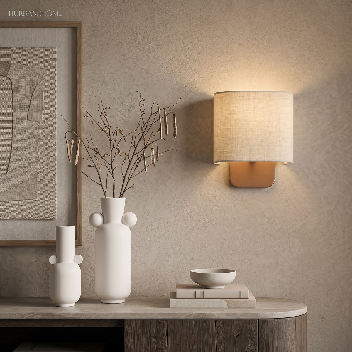 Linen shade sconce above a stone console with vases and books