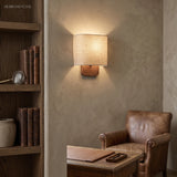 Linen shade sconce lighting a reading corner with leather armchair
