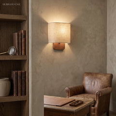 Linen shade sconce lighting a reading corner with leather armchair