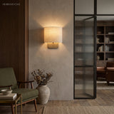 Linen shade wall sconce beside a fluted glass door and green chair