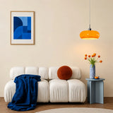 Orange glass pendant light above a sofa side table in a living room