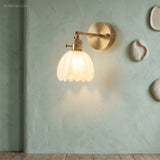 White lotus glass wall sconce glowing against a sage green wall