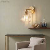 Clear scalloped glass sconce above a slim console and pale armchair