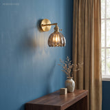 Smoked lotus glass sconce on a blue wall above a wooden console