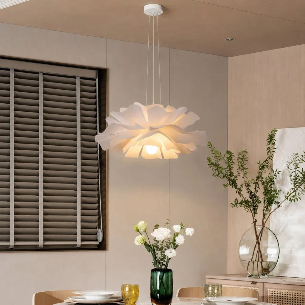 White lotus pendant light glowing over a dining table by shuttered windows