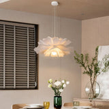 White lotus pendant light glowing over a dining table by shuttered windows