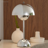 Chrome table lamp beside ceramic vases against a walnut panelled wall