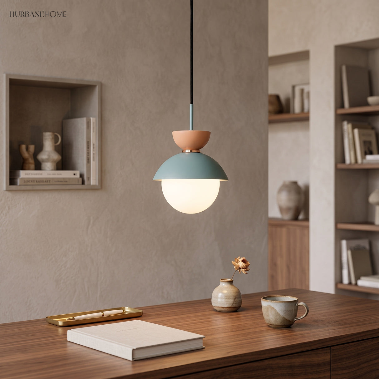 Green-grey metal dome pendant light glowing above a walnut desk with a ceramic vase