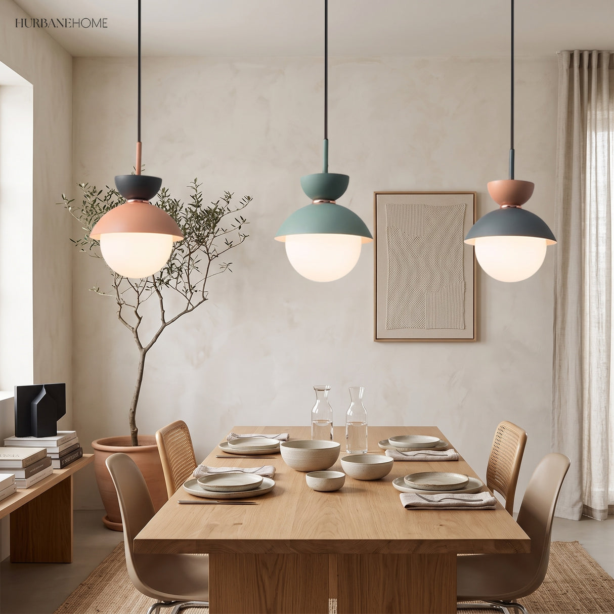 Three macaron pendant lights in pink, grey and blue hanging above a dining table