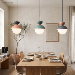 Three macaron pendant lights in pink, grey and blue hanging above a dining table