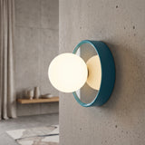 Blue orb wall sconce with a frosted glass globe on a concrete wall