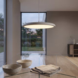 Grey disc pendant light glowing above a glass dining table with two ceramic bowls