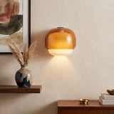 Two-tone amber and opal glass wall sconce mounted above a walnut console