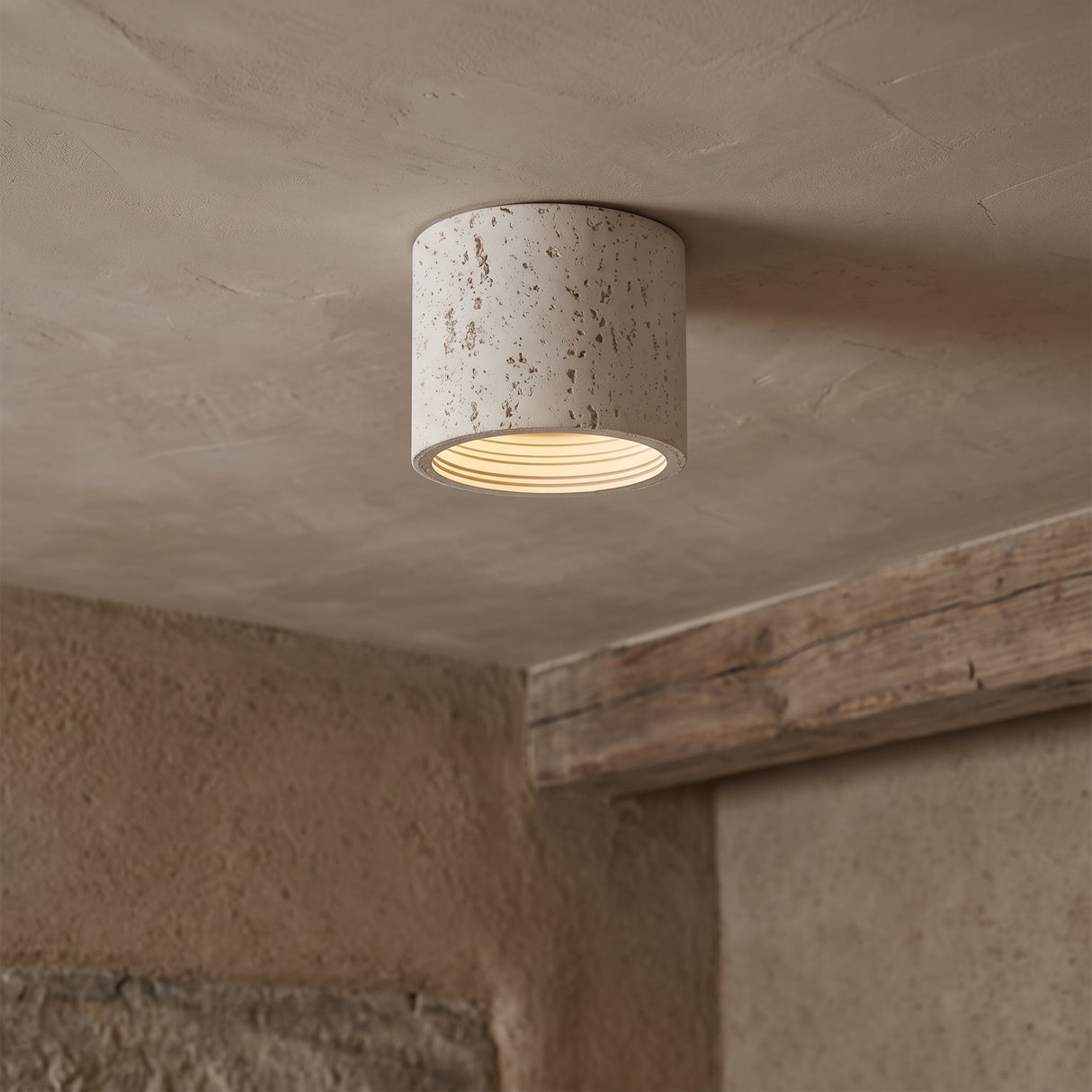 Cream travertine-textured cylinder ceiling light surface-mounted on a plaster ceiling
