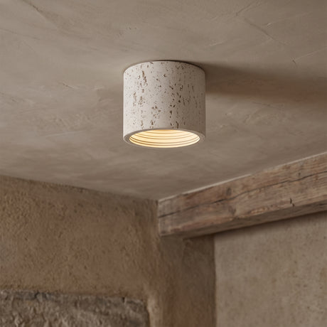 Cream travertine-textured cylinder ceiling light surface-mounted on a plaster ceiling