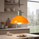Orange glass bowl pendant light with olive green metal cap and brass neck