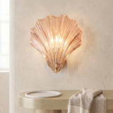 Amber glass shell wall sconce on a brass base against a pale plaster wall