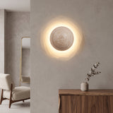Round travertine stone LED wall sconce glowing warm on a plain wall