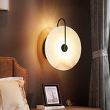 Marble sconce lit beside a bed with a framed photo and curtain