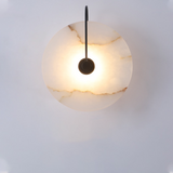 Marble disc sconce on a black curved arm against a pale wall